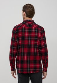 Camicia di flanella a quadri rossi e neri con maniche lunghe, polsini a bottoni e colletto classico. Tessuto morbido con vestibilità rilassata.