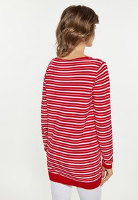 Maglietta a maniche lunghe rossa e bianca con colletto crew e polsini a coste. Texture morbida e vestibilità comoda. Lunghezza che supera la vita.