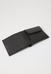 Sort læderpung med flere kortslots, en fold-over flap og en glat tekstur. Har præget logo og syede kanter.