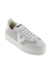 Zapatillas blancas con paneles de malla y ante gris, puntera redonda, cordones planos blancos y una etiqueta negra con "victoria" en la lengüeta.