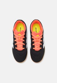 Czarne buty sportowe z siateczkowymi wstawkami, białymi akcentami, jaskrawymi pomarańczowymi sznurówkami i teksturowaną podeszwą. Wnętrze ma jaskrawożółtą wkładkę.