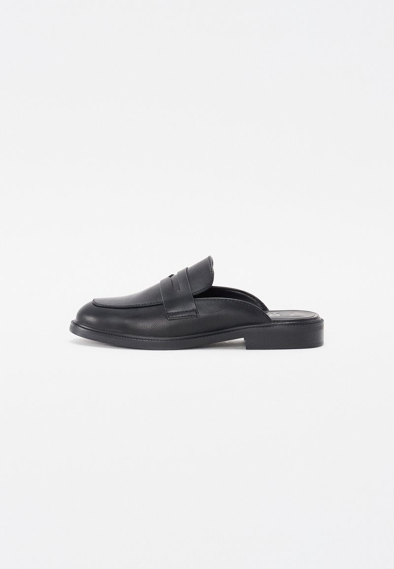Mocassin noir en cuir, à enfiler, avec petit talon et détails cousus, conçu pour un port facile et une utilisation décontractée ou formelle.