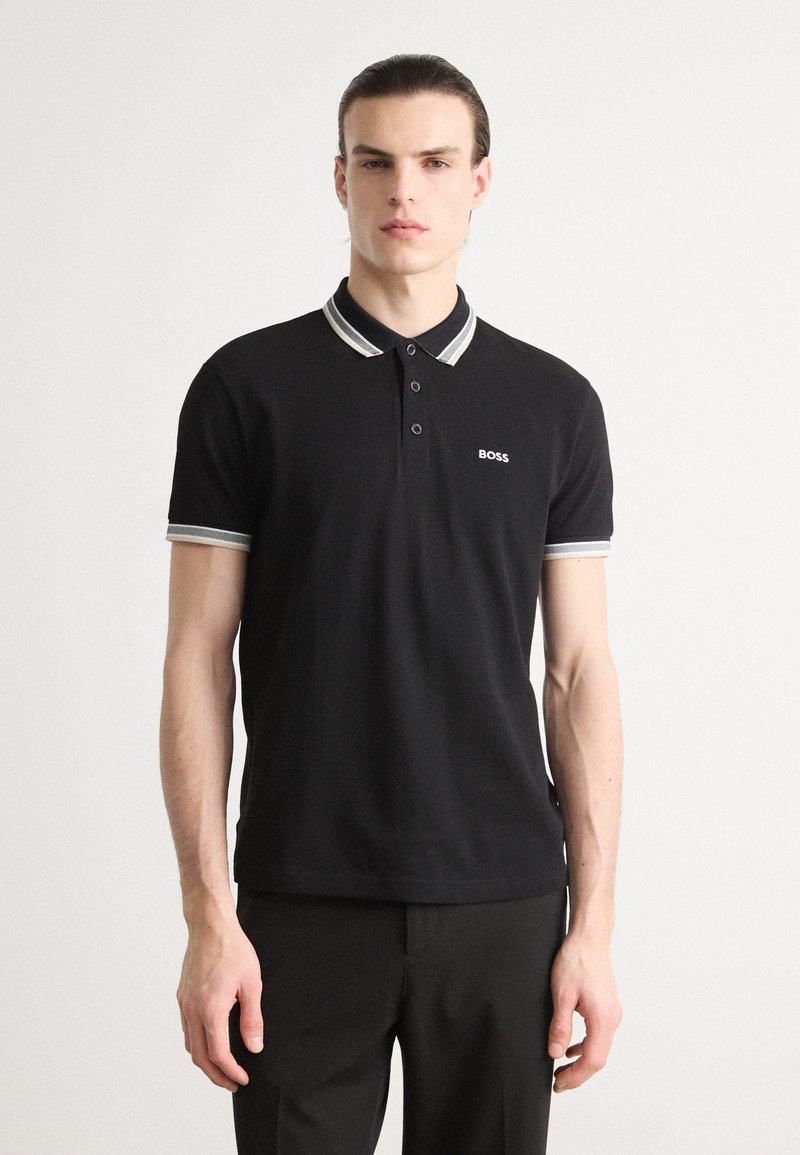 Schwarzes Poloshirt mit kontrastierenden Kragen- und Ärmelakzenten. Verfügt über drei Knöpfe und ein kleines "BOSS"-Logo auf der Brust. Glatte Textur.