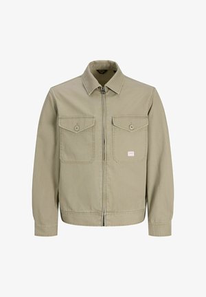 Béžová bunda na zip s špičatým límcem, dvěma kapsami na prsou na knoflíky, dlouhými rukávy a malou obdélníkovou nášivkou na levé kapse.