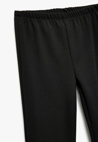 Pantalons extensibles noirs avec une taille élastique, texture lisse et coupe fuselée. Conçus pour le confort et la liberté de mouvement.