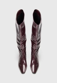 Burgundy patent leather ankle boots with a slouchy design, pointed toes, and a smooth texture.