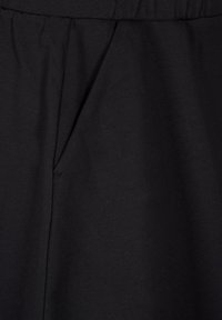 Mustaa kangasta, jossa on sileä pinta ja hillitty kiilto. Yksi laskosvyötärön lähellä ja yksinkertainen muotoilu.