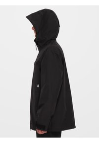 Czarna wodoodporna kurtka z kapturem, z zapięciem na suwak z przodu, elastycznymi mankietami i detalem logo po lewej stronie. Gładka tekstura, luźny krój.
