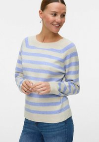 Maglione beige chiaro con righe orizzontali blu, collo a giro e polsini a coste. Texture morbida abbinata a una vestibilità casual. Jeans di denim visibili.