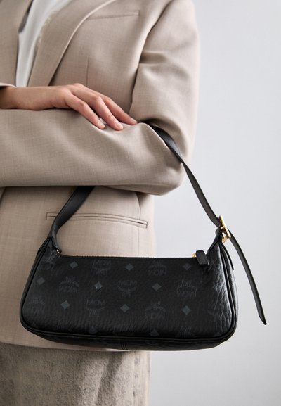 Black leather handbag with embossed MCM logo pattern, rectangular shape, slim handle, and gold-tone hardware accent.