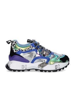 Zapatilla multicolor con detalles metálicos en plata, azul, verde, púrpura y estampado animal, suela blanca gruesa y cordones en blanco y negro con patrón.