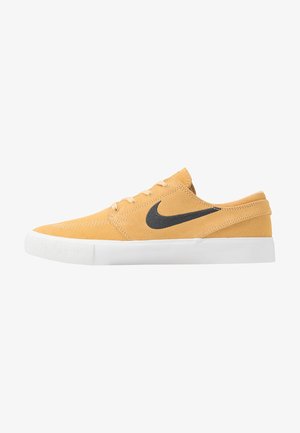 Des chaussures Nike avec une tige en daim jaune, un logo noir, une semelle en caoutchouc blanc, un design à lacets et une texture lisse avec des accents minimaux.
