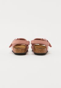 Rosa syntetiska sandaler med en korkfotbädd. Har justerbara remmar för en bättre passform och en texturerad svart gummisula. Bakre vy.
