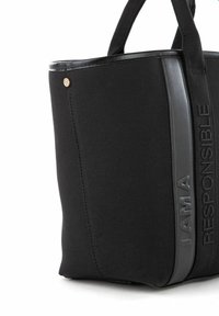Bolso tote negro con tela texturizada, elegantes acentos negros y logotipo en relieve "SOY UNA PERSONA RESPONSABLE" en el costado. Asa resistente para transportar.