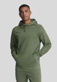 Grüne Kapuzenjacke mit Kängurutasche, verstellbarem Kapuzenzug und kleinem gelben Logo auf der Brust. Glatter Stoff und taillierte Passform.