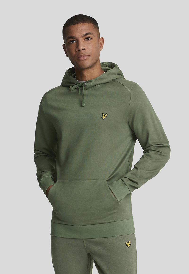 Grüne Kapuzenjacke mit Kängurutasche, verstellbarem Kapuzenzug und kleinem gelben Logo auf der Brust. Glatter Stoff und taillierte Passform.