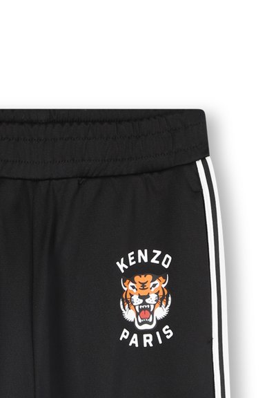 Czarne dresy z elastycznym pasem, białe paski po bokach oraz grafika tygrysa z napisem "KENZO PARIS" w grubym kroju czcionki na przodzie.