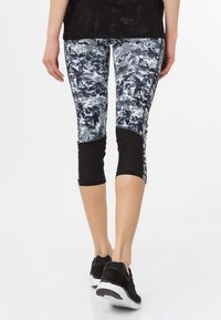 Leggings capri noir et blanc avec un motif floral et rayé, dotés d'un bas de jambe noir uni et d'une taille élastique.