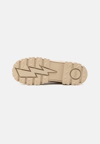 Suela de goma beige de moda con profundos surcos y un patrón en zigzag, con un logo redondo y una textura resistente que proporciona mejor agarre y durabilidad.