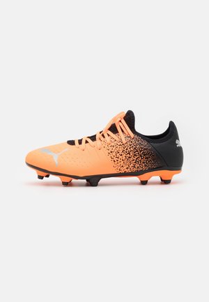 Chaussure de football orange et noire avec lacets, dessus texturé et crampons sous la semelle sur fond blanc.