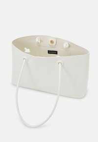 Biała torba tote z cienkimi sznurkami, otwartym górnym brzegiem, wewnętrzną kieszonką na zsużone przedmioty i zapięciem na magnes na białym tle.