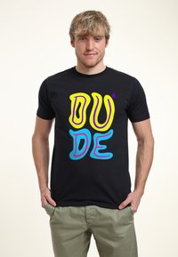 Camiseta negra con un atrevido y colorido texto "DUDE" en amarillo, rosa y azul. Tejido suave con un corte estándar y diseño de cuello redondo.