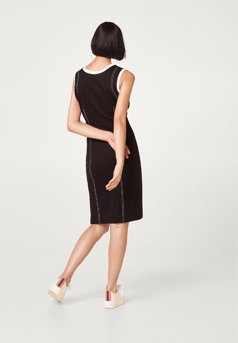 Czarna sukienka bez rękawów z kontrastowym białym przeszyciem, do kolan, dopasowany krój, gładka tekstura, noszona z platformami.