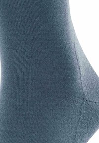 Ciemnoniebieska skarpetka o gładkiej fakturze, z delikatnym prążkowanym wzorem i wzmocnioną piętą, przedstawiona z kątowego widoku.