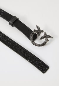 Curea neagră din piele cu bandă texturată, având accente din cristale negre. Catarama are forma a două păsări, fiind de asemenea împodobită cu cristale.