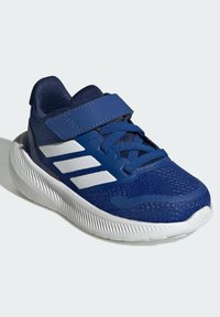 Blue athletic shoe with mesh upper, white accents, and hook-and-loop strap. Features a textured sole for grip and support.