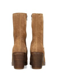 Botines de ante marrón con tacón apilado, cierre de cremallera y textura suave. Presentan una punta redondeada y un diseño simple.