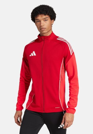 Rode sportjack met een volledige rits, gemaakt van gladde stof. Heeft witte accenten en drie witte strepen op de schouders.