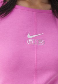Pink cotton athletic top featuring a round neckline, short sleeves, and a white embroidered "Nike AIR" logo. Smooth texture with visible stitching.