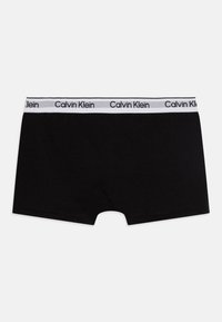 Mustad mustad aluspesu, millel on valge elastne vöökoht, kus on must „Calvin Klein” logo. Pehme puuvillane materjal, tavaline sobivus, ilma mustriteta.