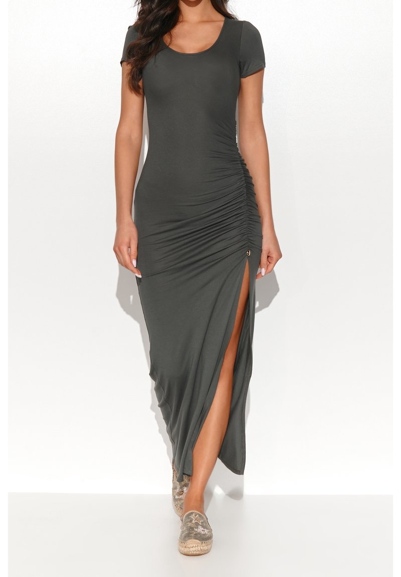 Femme portant une robe maxi froncée gris foncé à manches courtes et fente latérale, associée à des chaussures slip-on à motifs.