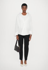 White button-up shirt, black tapered pants, white pointed flats, and a dark bag. Simple design, smooth texture, and well-defined shapes.