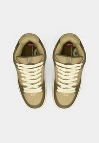 Adidași bej și verde măsliniu, cu un amestec de suede și plasă, cu sireturi bej și o talpă din cauciuc, evidențiind un design aerodinamic.