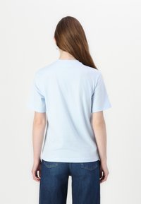 Camiseta de algodón de color azul claro con mangas cortas, un cuello redondo y una textura suave; combinada con pantalones de mezclilla azul oscuro.