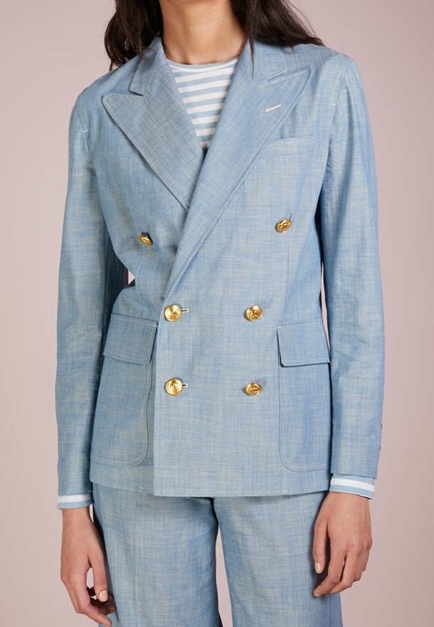 Světle modrý dvouřadový blazer vyrobený z texturované látky, s zlatými knoflíky, výraznými klopami a dvěma předními kapsami.