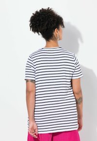 Bomulds t-shirt med sort og hvid vandret striber, rund hals, korte ærmer og en afslappet pasform. Bemærkelsesværdigt bagdesign med strikket detalje.
