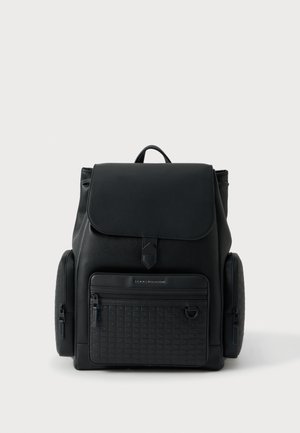 Mochila de cuero negro con acabado texturizado, cierre superior con solapa, bolsillo frontal con cremallera y ruedas laterales para facilitar el transporte.