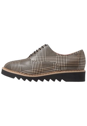 Mustavalkoinen houndstooth-kuvioidut oxford-kenkät, joissa on siksak-kuvioitu pohja ja nauhakiinnitys. Kiiltävä pinta, keskikorkeus ja pyöreä kärki.