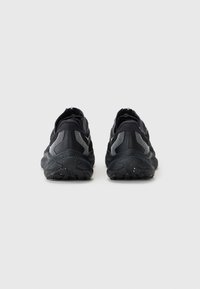 Baskets de sport noires avec une tige en mesh texturé, semelle en caoutchouc et accents réfléchissants. Présentent un col rembourré et une fermeture éclair à l'arrière.