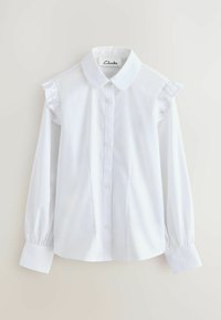 Camicia bianca a maniche lunghe con colletto classico, chiusura a bottoni frontale e dettagli arricciati sulle spalle. Tessuto morbido e design elegante.