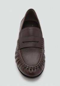 Mocasines de cuero marrón con punta redondeada, que cuentan con una suela plana, una banda decorativa en el empeine y detalles cosidos a lo largo de los lados.