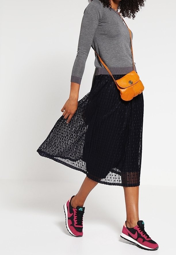 Grå langærmet bluse, sort plisseret midiskørt, orange crossbody taske og pink Nike sneakers. Har tekstureret stof og casual stil.