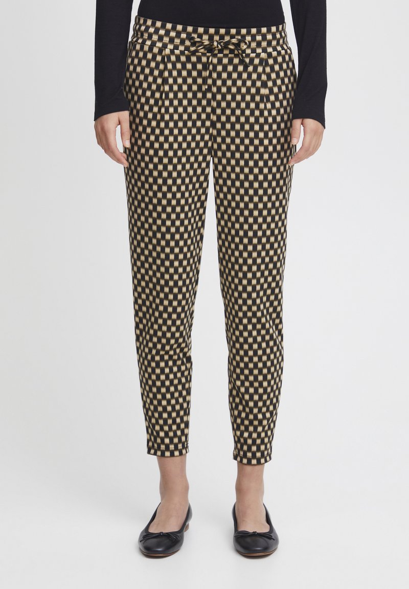 Pantalones a cuadros en negro y dorado con cintura con lazo, piernas ajustadas, parte delantera plana y bolsillos, combinados con bailarinas negras.