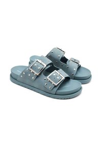 Las chanclas de goma azul cuentan con dos correas anchas con grandes hebillas de plata y remaches decorativos a lo largo de los bordes. Suela texturizada.