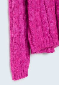 Różowy sweter z warkoczy wykonany z miękkiej przędzy, z prążkowanym dołem i mankietami. Tekstura jest puszysta, z wypukłymi wzorami na całej powierzchni.