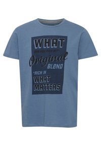 Blå T-shirt med korte ærmer lavet af bomuld. Har et stort grafisk print med tekst i forskellige skrifttyper og farver centreret på forsiden.